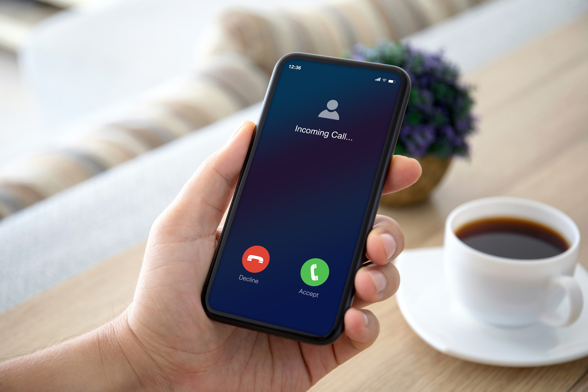 Dłoń trzyma telefon, na którym widać połączenie przychodzące przekierowane z innego numeru