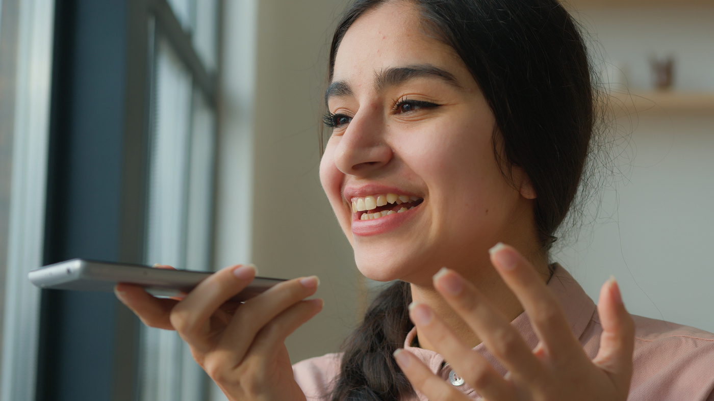 Kobieta włączyła mikrofon w telefonie i prowadzi rozmowę telefoniczną.