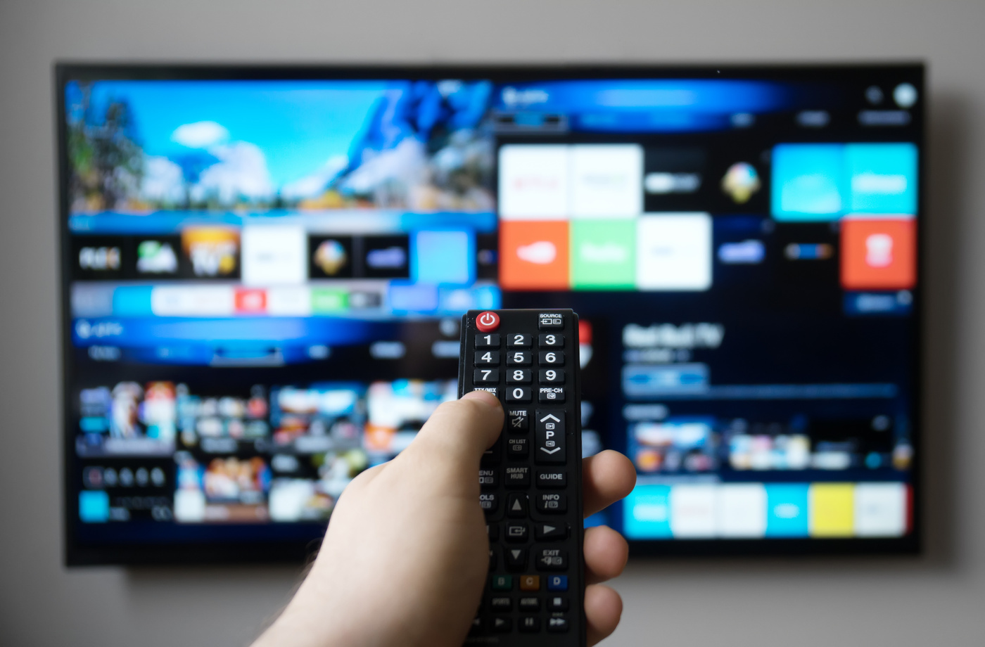 Widok dłoni z pilotem, włączający Polsat Box Go na smart TV.