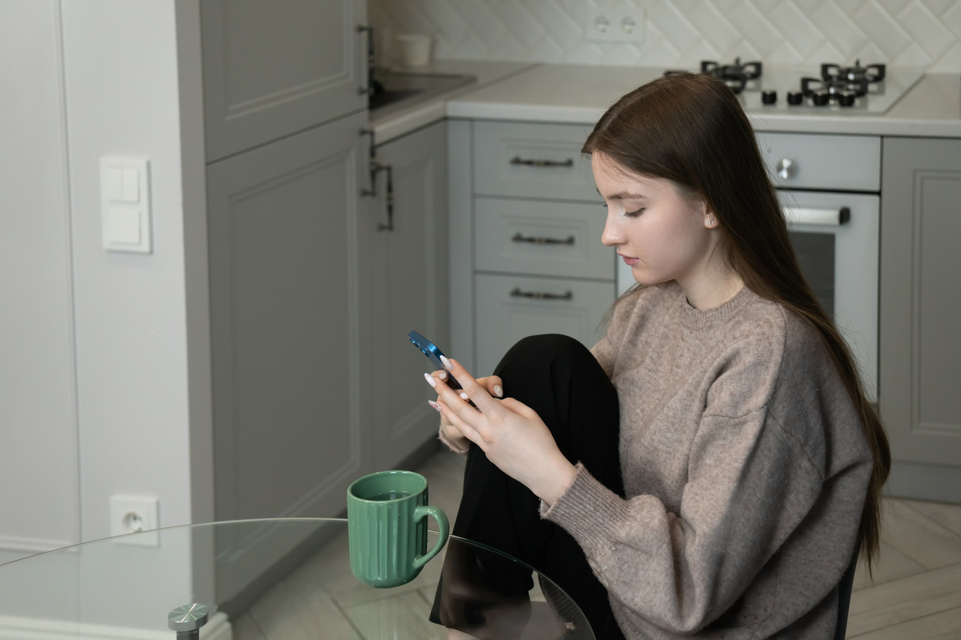 Kobieta siedzi przy stole i szuka informacji, czemu jej telefon często się przegrzewa.