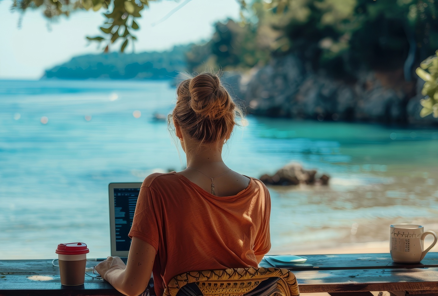 Kobieta na plaży pracuje na laptopie, bo w jej firmie możliwe jest workation.