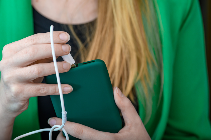 Kobieta podłącza telefon do ładowania, bo smartfon ma ciągle czarny ekran
