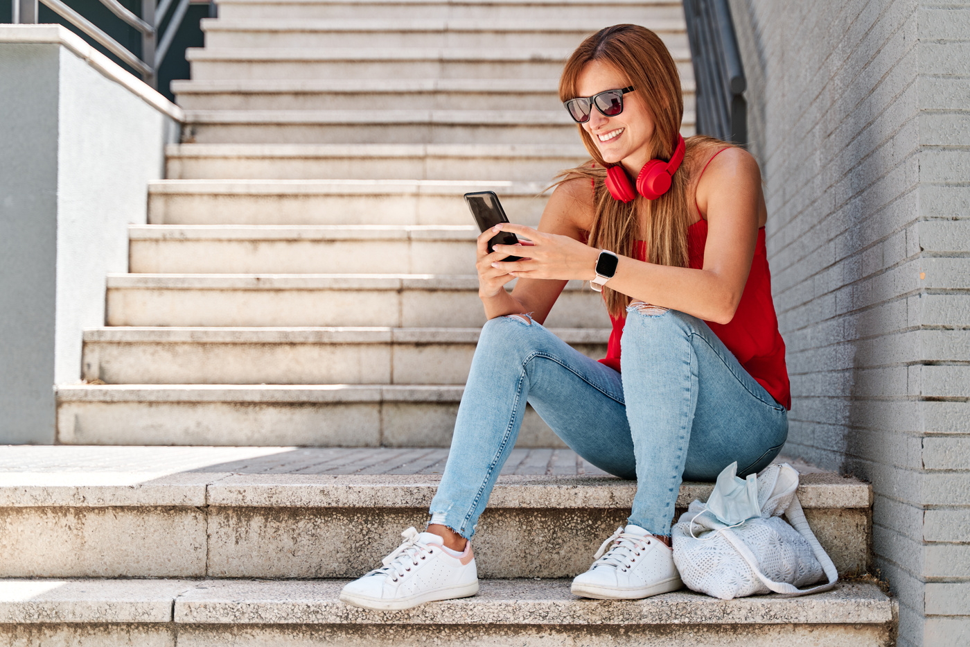 Kobieta siedzi na schodach na zewnątrz i przegląda funkcje telefonu Samsung Galaxy A37 5g.